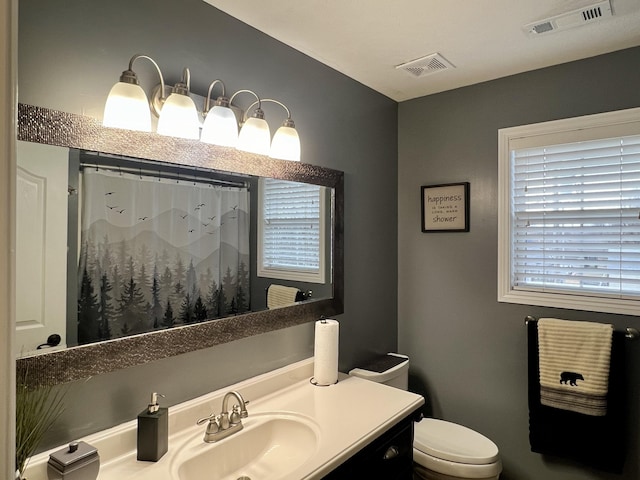 full bathroom featuring toilet, curtained shower, vanity, and visible vents