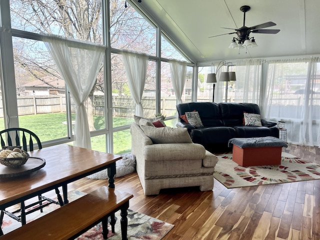 sunroom / solarium featuring wood finished floors, a wooden deck, and lofted ceiling