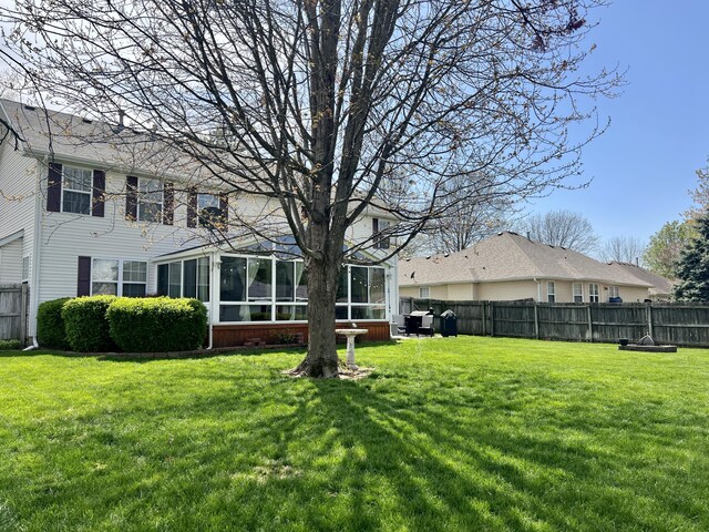 view of yard with fence and a sunroom