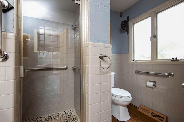 bathroom with a shower stall, visible vents, toilet, wainscoting, and tile walls