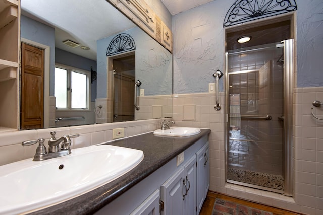 full bathroom featuring wainscoting, a sink, and a stall shower