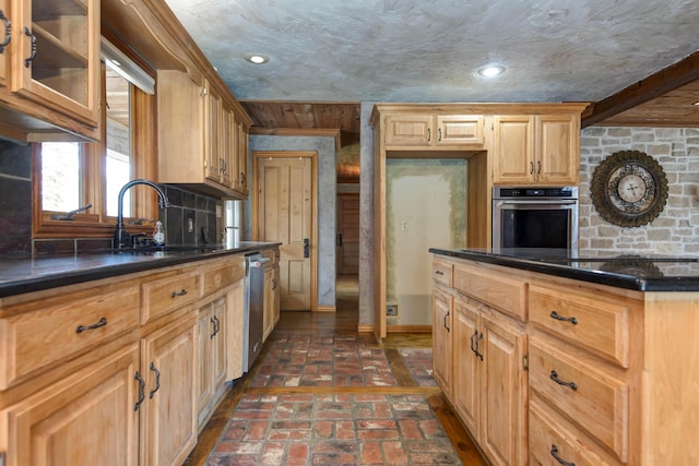 kitchen with recessed lighting, glass insert cabinets, stainless steel appliances, brick floor, and a sink