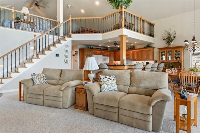 500 Navajo Trl, Kimberling City, MO 65686 - living room featuring plenty of natural light, stairway, a high ceiling, ceiling fan with notable chandelier, and light colored carpet
