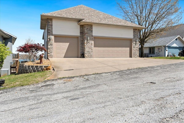 500 Navajo Trl, Kimberling City, MO 65686 - view of front of property featuring central air condition unit, stone siding, an attached garage, a shingled roof, and driveway