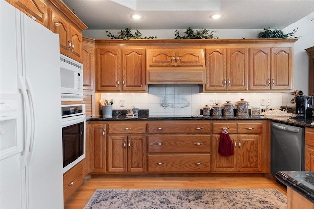 500 Navajo Trl, Kimberling City, MO 65686 - kitchen with dark stone countertops, brown cabinets, light wood finished floors, and white appliances