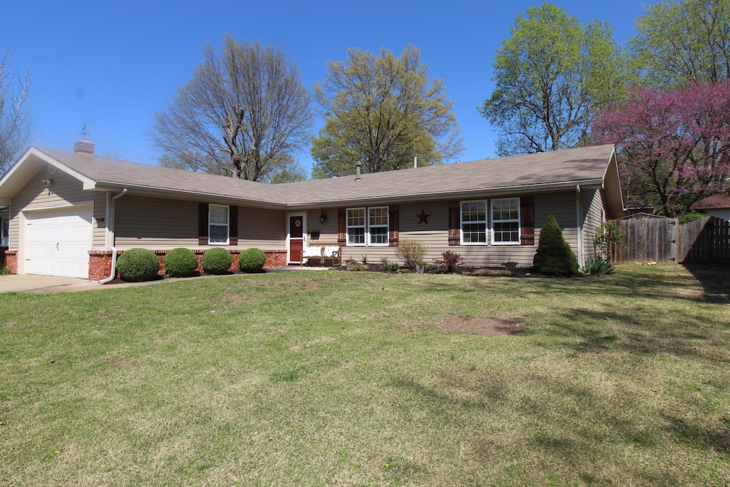 ranch-style home with a garage, fence, a front lawn, a chimney, and concrete driveway