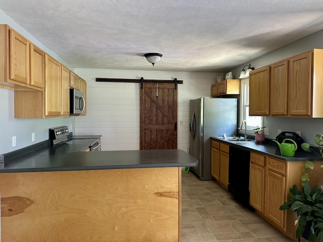 85 Peggy Ave, Mammoth Spring, AR 72554 - kitchen with appliances with stainless steel finishes, dark countertops, a barn door, a textured ceiling, and a peninsula