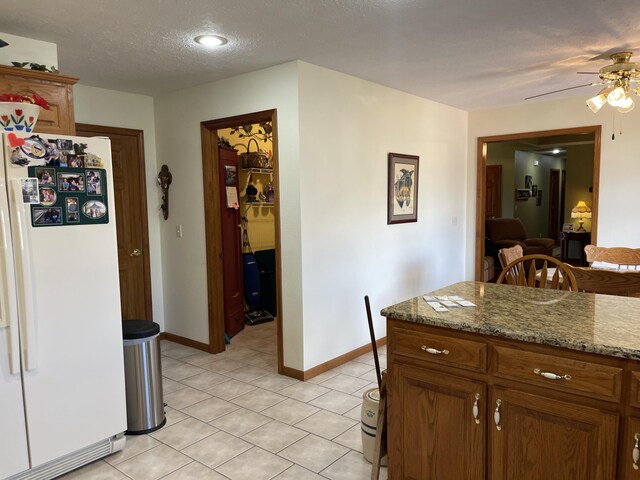 1605 S Meadow Ln, Bolivar, MO 65613 - kitchen with freestanding refrigerator, ceiling fan, a textured ceiling, light tile patterned flooring, and baseboards