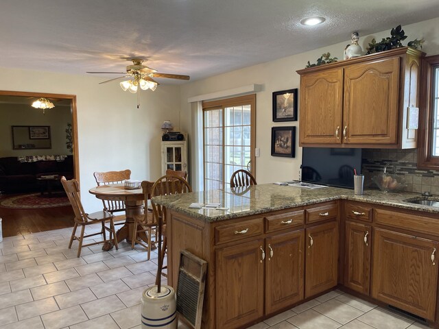 1605 S Meadow Ln, Bolivar, MO 65613 - kitchen with brown cabinetry, a peninsula, and a ceiling fan