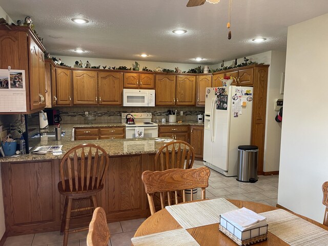 1605 S Meadow Ln, Bolivar, MO 65613 - kitchen featuring white appliances, light stone countertops, tasteful backsplash, a peninsula, and brown cabinets