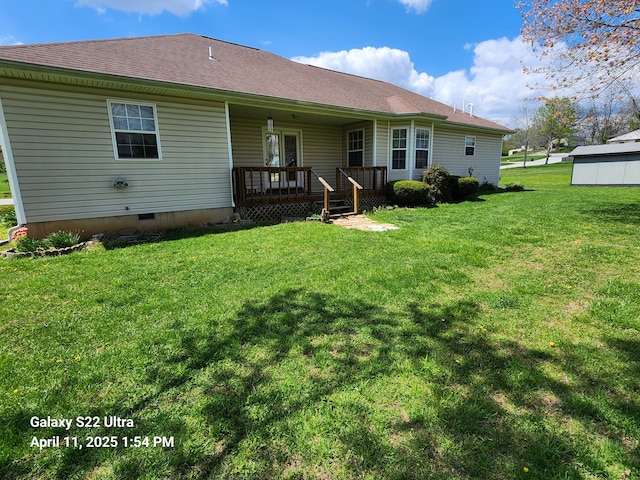 back of house featuring a yard, covered porch, and roof with shingles