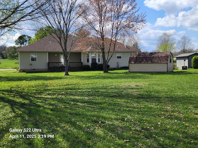 back of house with a yard, an outdoor structure, and a storage unit