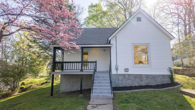 back of house featuring stairs, covered porch, a lawn, and roof with shingles