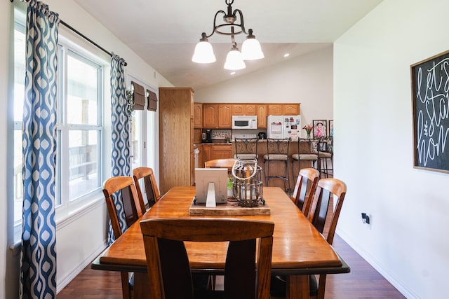 dining room featuring a chandelier, baseboards, dark wood-style floors, and lofted ceiling