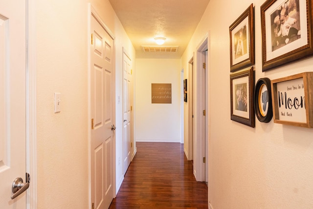 hallway with baseboards, dark wood-style floors, and visible vents