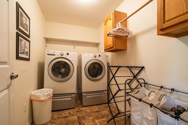 laundry area with separate washer and dryer, stone finish floor, baseboards, and cabinet space