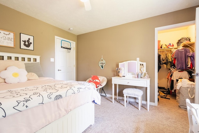 bedroom featuring light carpet, a spacious closet, a closet, and baseboards