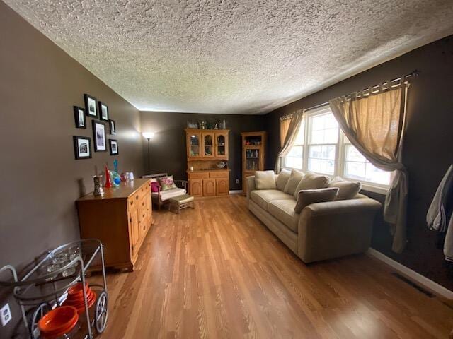 living area with visible vents, light wood finished floors, and a textured ceiling