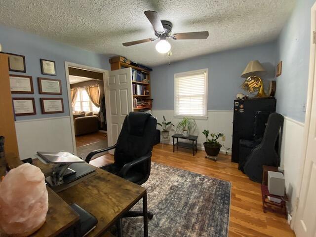 office featuring plenty of natural light, wainscoting, a textured ceiling, and ceiling fan