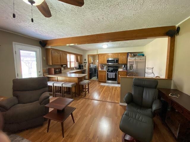 living room with light wood-style flooring, a ceiling fan, and a textured ceiling