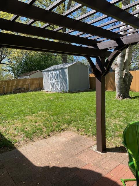 view of yard with a patio, an outdoor structure, a pergola, a shed, and a fenced backyard