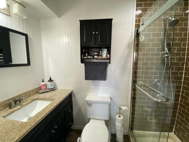 full bathroom with a shower stall, vanity, and toilet