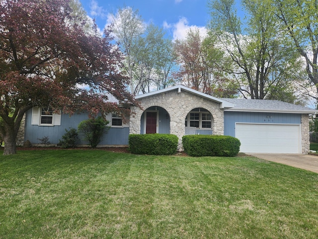 view of front facade with an attached garage, concrete driveway, a front yard, and stone siding