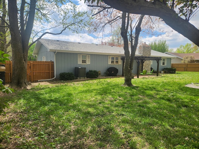 rear view of house featuring central AC, fence, a yard, and a chimney