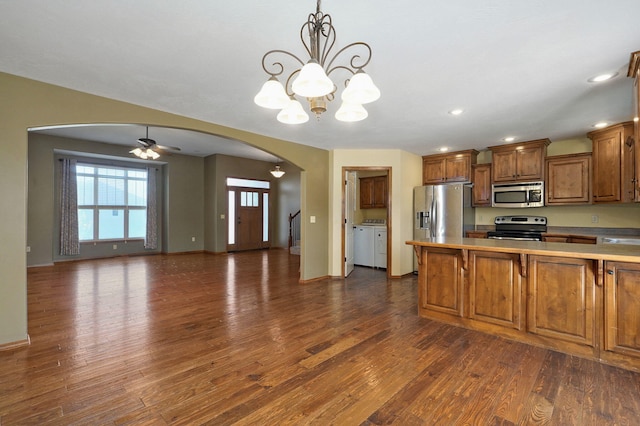 3684 Bridgewood Ave N, Springfield, MO 65803 - kitchen featuring stainless steel appliances, washer and clothes dryer, arched walkways, dark wood-type flooring, and brown cabinetry