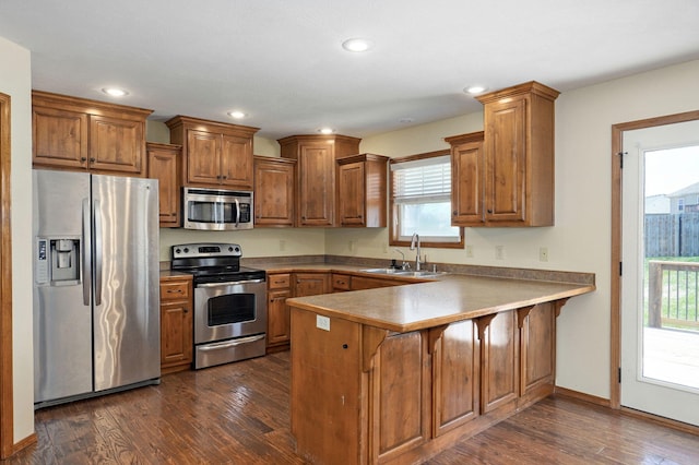 3684 Bridgewood Ave N, Springfield, MO 65803 - kitchen with brown cabinetry, a peninsula, stainless steel appliances, and a sink