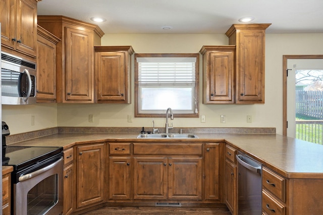 3684 Bridgewood Ave N, Springfield, MO 65803 - kitchen featuring brown cabinetry, a peninsula, appliances with stainless steel finishes, and a sink