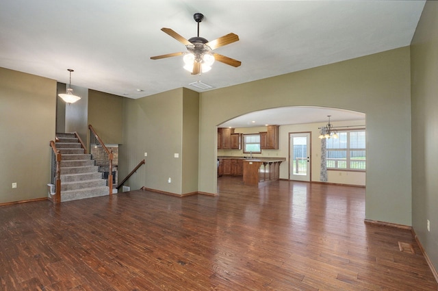 3684 Bridgewood Ave N, Springfield, MO 65803 - unfurnished living room with ceiling fan with notable chandelier, baseboards, arched walkways, and dark wood-type flooring