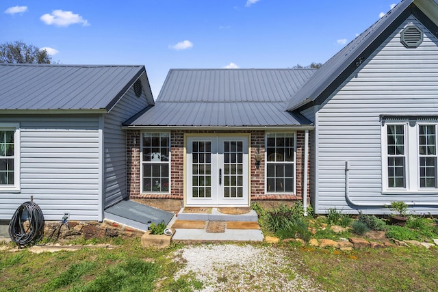 rear view of property with brick siding, french doors, and metal roof
