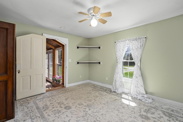 carpeted spare room with ceiling fan and baseboards