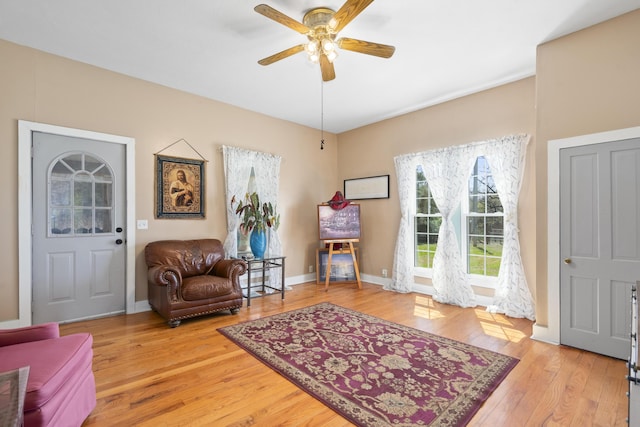 sitting room featuring light wood finished floors, baseboards, and a ceiling fan