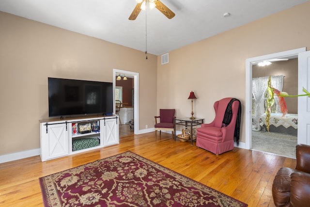 living room with visible vents, baseboards, light wood-type flooring, and a ceiling fan