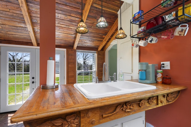 kitchen featuring wooden ceiling, decorative light fixtures, lofted ceiling with beams, a sink, and butcher block countertops