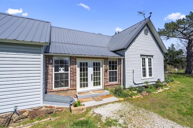 back of property with brick siding, french doors, and metal roof