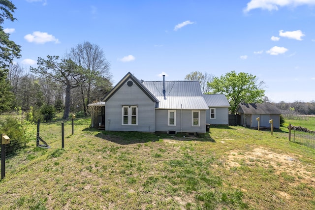back of property with metal roof, fence, and a lawn
