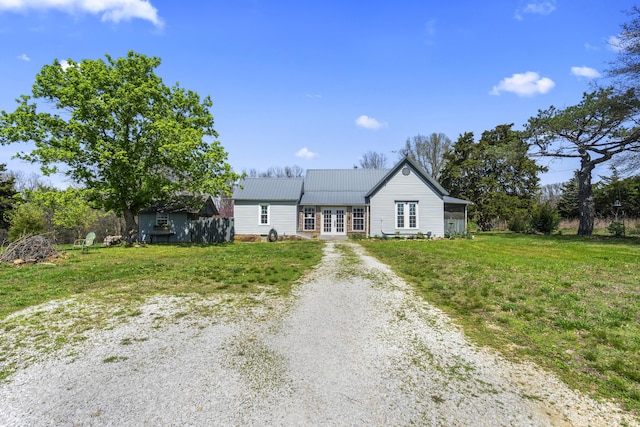 single story home with a front yard, french doors, metal roof, and driveway
