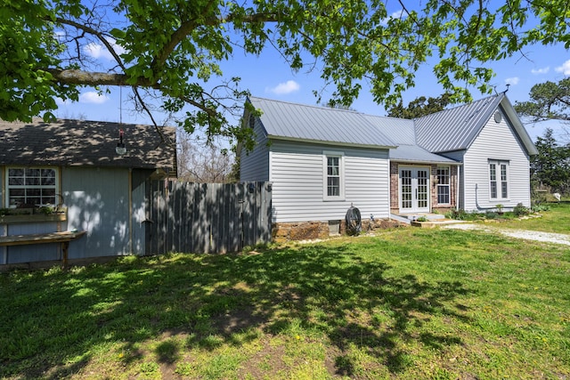 view of front of property featuring french doors, metal roof, fence, and a front lawn
