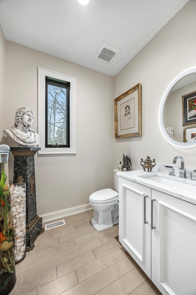bathroom featuring toilet, wood finished floors, vanity, and baseboards