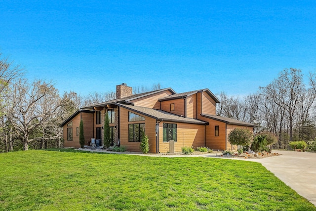 view of front of home with a chimney, a front lawn, and driveway