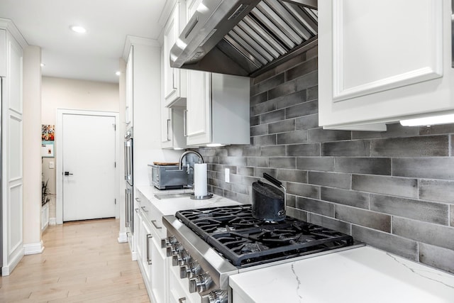 kitchen with range hood, white cabinets, tasteful backsplash, light stone counters, and recessed lighting