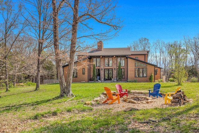 back of property featuring a fire pit, a chimney, and a yard