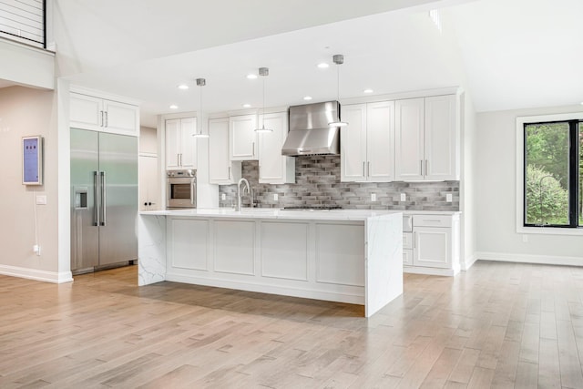 kitchen featuring appliances with stainless steel finishes, wall chimney range hood, light wood-type flooring, baseboards, and recessed lighting