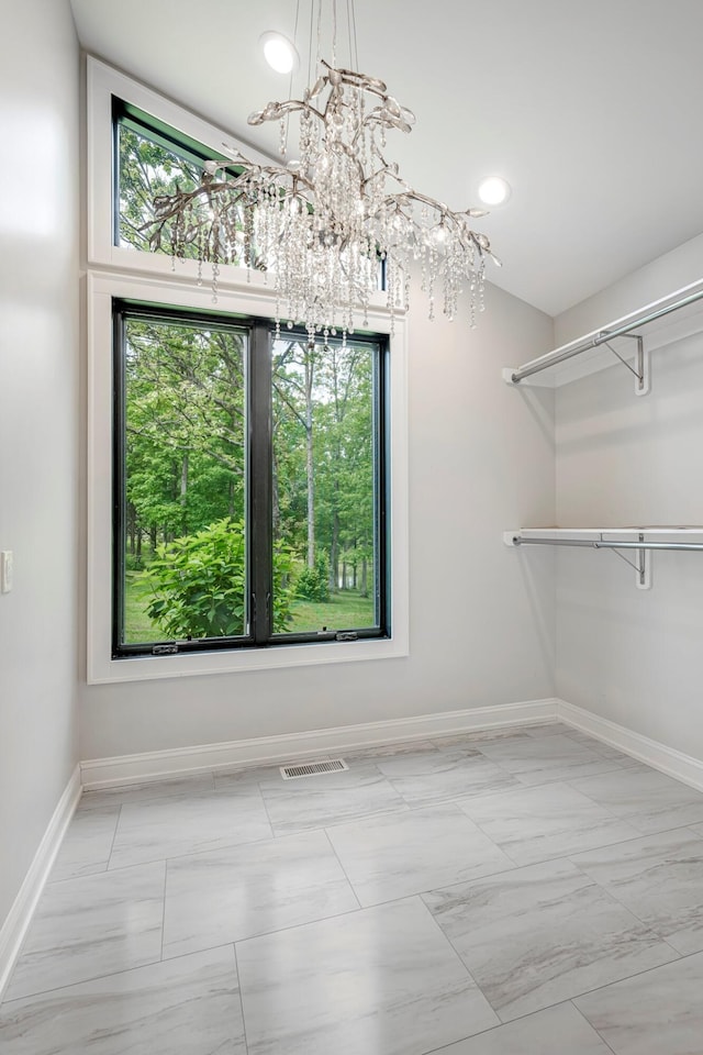 unfurnished dining area with a chandelier, baseboards, plenty of natural light, and marble finish floors