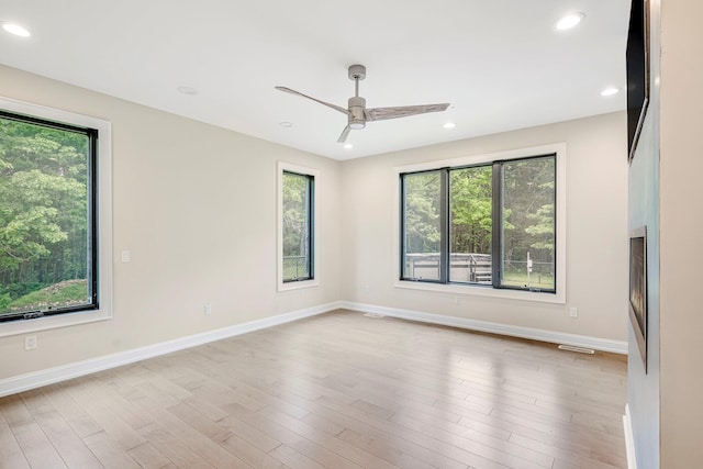 empty room with healthy amount of natural light, ceiling fan, wood finished floors, recessed lighting, and baseboards