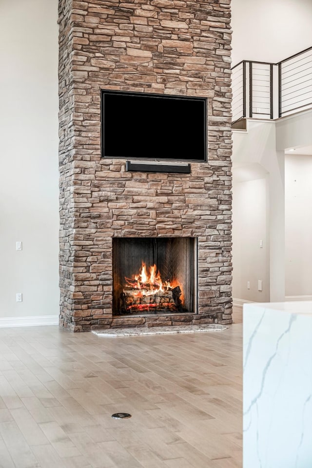 detailed view of a fireplace, wood finished floors, and baseboards