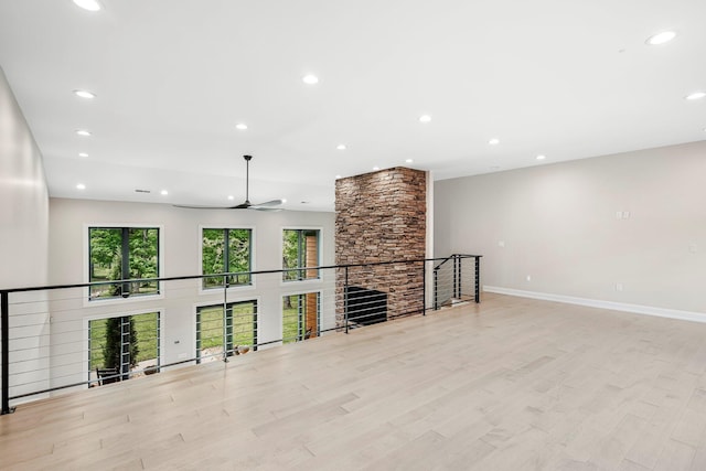 unfurnished living room with a ceiling fan, recessed lighting, wood finished floors, baseboards, and a stone fireplace